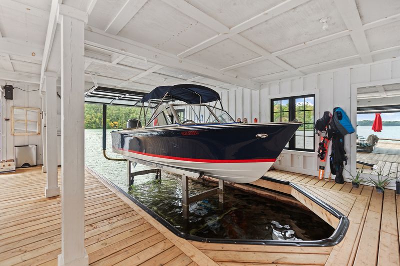 Boat on hydraulic lift inside white boathouse